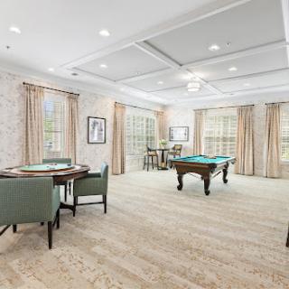 A spacious and elegantly designed game room featuring a pool table and a cozy dining area.