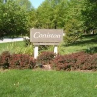 A sign labeled 'Coniston' surrounded by lush greenery and bushes.
