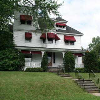 A large house with red awnings and a well-maintained lawn.