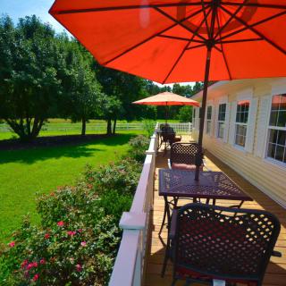 A peaceful patio with outdoor seating and umbrellas overlooking a lush garden.