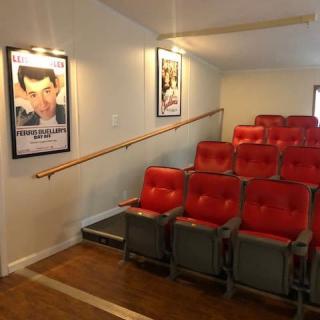 A small theater interior with red cushioned chairs and movie posters on the walls.