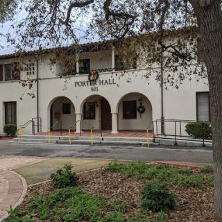 A view of the entrance to a building named 'Home Hall', featuring arched doorways and landscaped surroundings.