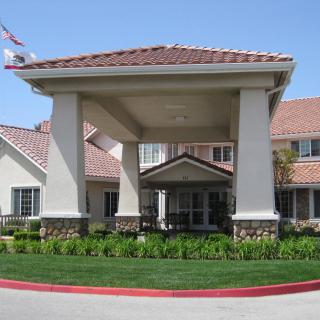 A residential building with a covered entrance and well-maintained landscaping.
