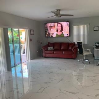 A modern living room with a red sofa, marble flooring, and a large television on the wall.