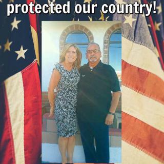 A couple stands proudly in front of American flags, symbolizing patriotism and gratitude for service.
