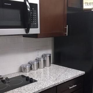 Modern kitchen with a microwave, storage jars, and sleek countertop.