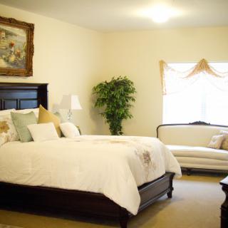 A cozy bedroom with a large bed, a couch, and decorative elements.