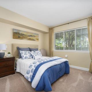 A cozy bedroom with a neatly made bed and large window.