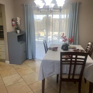A cozy dining area with a table set for four, decorated with flowers near a window with light blue curtains.
