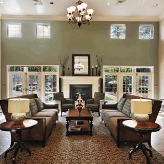 A beautifully designed living room with sofas arranged around a central fireplace, enhanced by large windows and elegant decor.