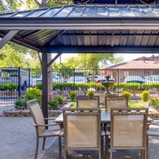 Outdoor patio with a gazebo and dining furniture set in a garden setting.