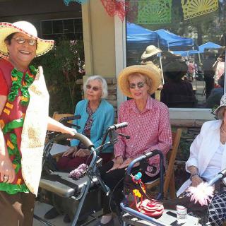 A group of elderly women wearing hats enjoying a sunny day outdoors.