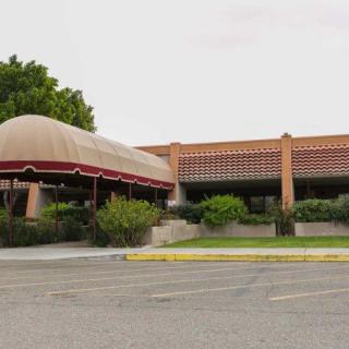 A restaurant exterior with a large awning and an empty parking lot in a desert setting.