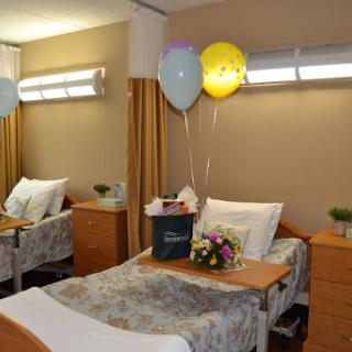 A cozy hospital patient room decorated with balloons and flowers.