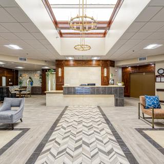 A modern lobby with a reception desk, stylish seating, and a decorative chandelier.