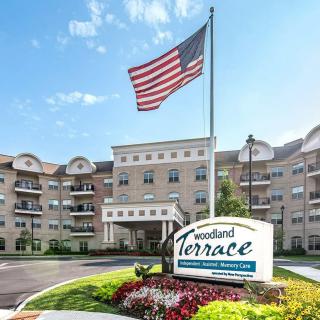 A large retirement home with a prominent American flag and well-maintained landscaping.