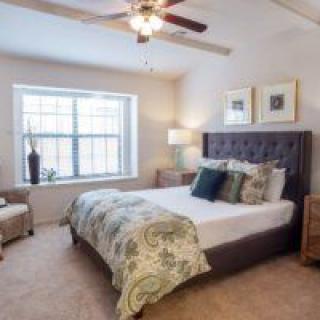A cozy and modern bedroom featuring a large bed, stylish decor, and natural light streaming through a window.