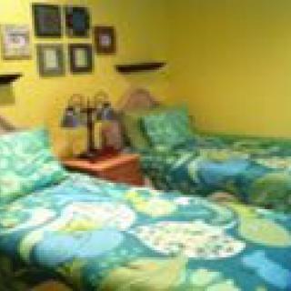 A vibrant bedroom with twin beds featuring colorful bedding, adorned with wall art and decorative lamps.