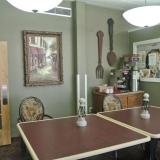 A cozy dining area with elegant decor, featuring tables and chairs, wall art, and a small counter for beverages.