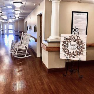 A welcoming hallway with rocking chairs and a decorative welcome sign.