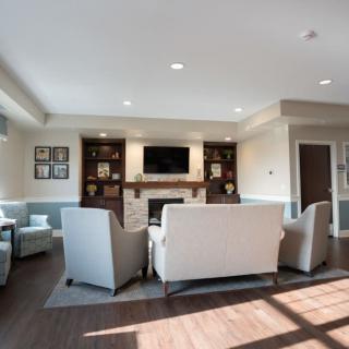 A modern living room featuring a cozy seating arrangement around a fireplace and television.