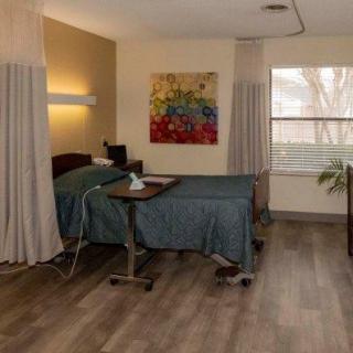 A clean and modern hospital room with a bed and medical equipment, decorated with colorful artwork on the wall.