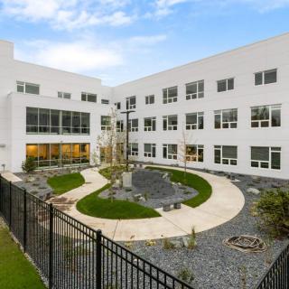 A modern commercial building with a landscaped courtyard and multiple windows.