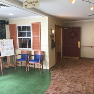 A small waiting area with chairs and a sign in a corridor.
