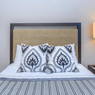A neatly made bed with patterned pillows and a bedside lamp in a modern bedroom.