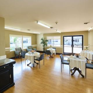 A clean and well-lit dining area with several small tables and chairs arranged throughout the space.