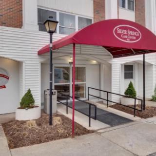 Front entrance of a building with a red awning and accessibility ramp.