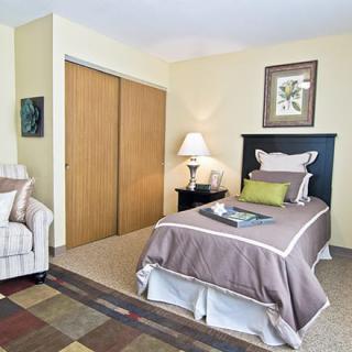 A cozy bedroom featuring a single bed, side table with a lamp, and minimalist decor.