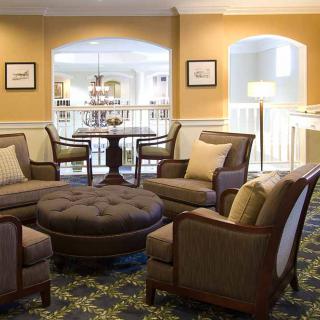 A cozy living room area with armchairs and an ottoman arranged in a circle.
