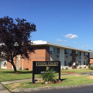 An exterior view of an apartment building with a sign labeled 'Living Court'.