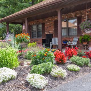 A beautifully landscaped front yard featuring vibrant flowers and cozy outdoor seating.
