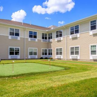 A sunny view of a residential building with a well-maintained lawn and clear blue sky.