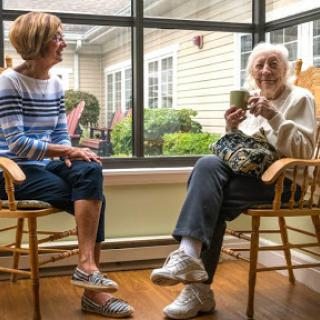 A warm conversation between two women in a sunlit room.