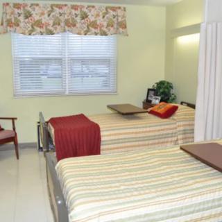 A hospital room with two neatly made twin beds, each equipped with overbed tables.