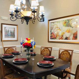 A beautifully set dining room table with elegant decor and a chandelier overhead.
