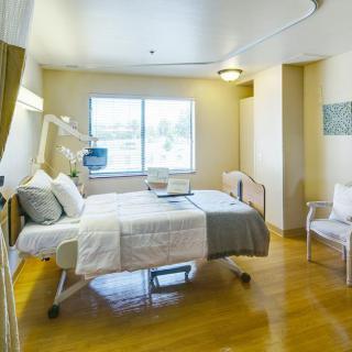 A modern and clean hospital room with a single patient bed and a large window.