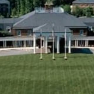 A large building with a green lawn in front, featuring several flagpoles.