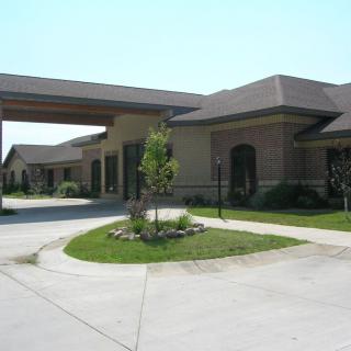 A modern building with a covered entrance and landscaped surroundings.
