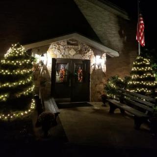 A cozy entrance adorned with Christmas lights and wreaths at night.