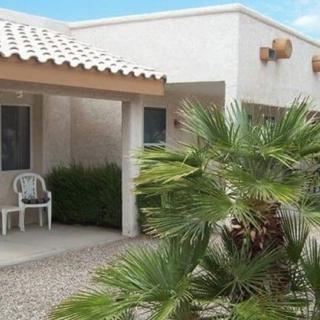 A residential house with a porch and palm tree in an arid climate setting.