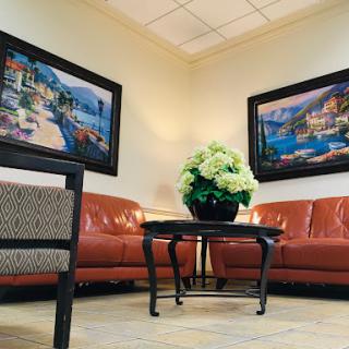 A cozy waiting area featuring comfortable sofas, a coffee table, and decorative artwork on the walls.