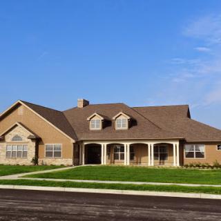 A beautiful single-family home with a spacious front yard and clear blue skies.