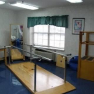 A rehabilitation room equipped with parallel bars and other exercise equipment.
