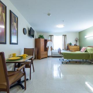 A well-lit room with a bed, table, chairs, and wall decorations.