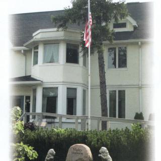 A two-story house with an American flag in the front yard.