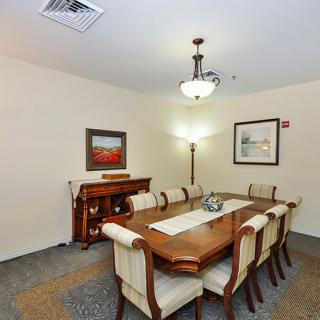 A well-decorated dining room with a large wooden table, upholstered chairs, and elegant lighting.